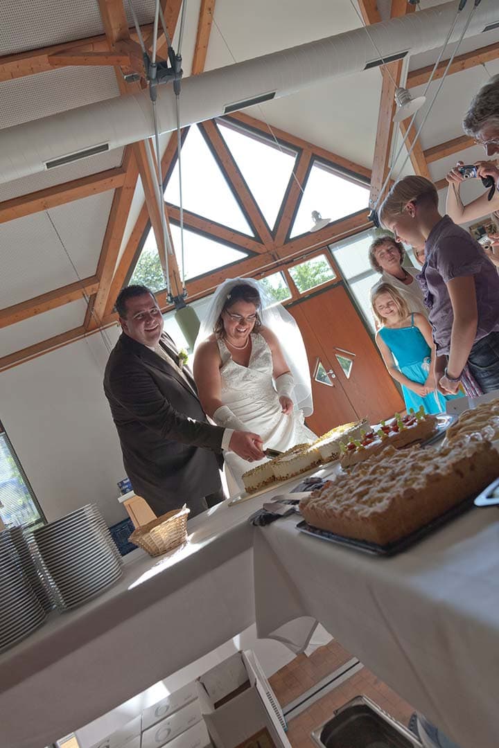 Unbearbeitetes RAW-Foto eines Brautpaars beim Anschneiden der Hochzeitstorte in heller Umgebung